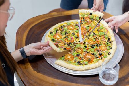Friends hand taking slice of fresh pizza togetherの写真素材