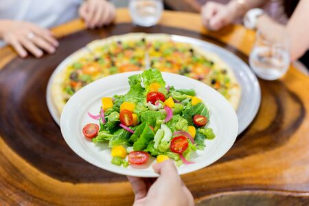 Waiter serving fresh vegetable salad in restaurantの写真素材