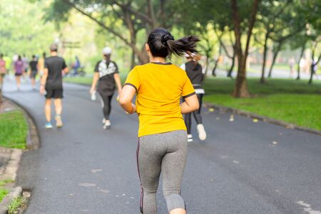 Woman exercise jogging in park with blurred people in backgroundの写真素材