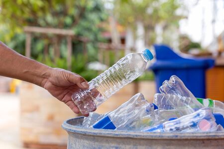Hand holding recyclable plastic bottle in garbage bin for cleaning.の写真素材