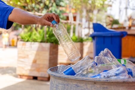 Hand holding recyclable plastic bottle in garbage bin for cleaning.の写真素材