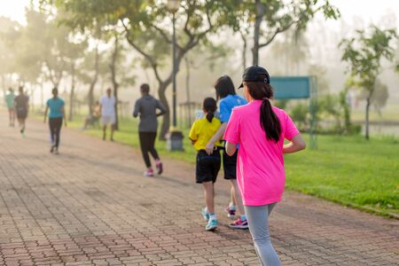 Woman exercise jogging in park with blurred people in background.の写真素材