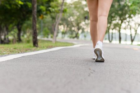 Young fitness woman legs walking exercise in public park in morningの写真素材