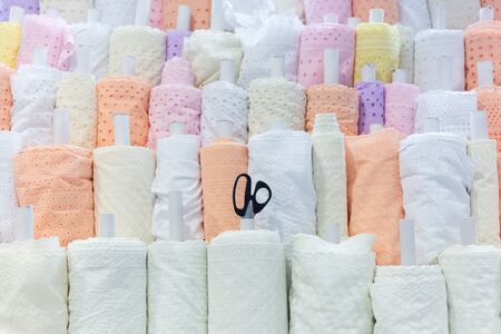 Rolls of bright colored fabric with scissors in the store.