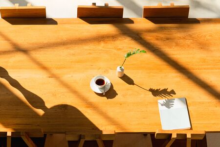 Bright room in shadow of the sunlight with coffee on wooden table and magazine.の写真素材