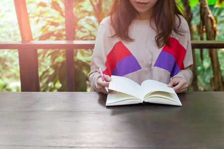 Young female hands holding open blank notepad and pen on the table.