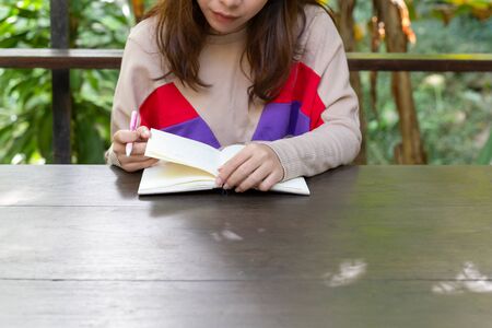 Young female hands holding open blank notepad and pen on the table.