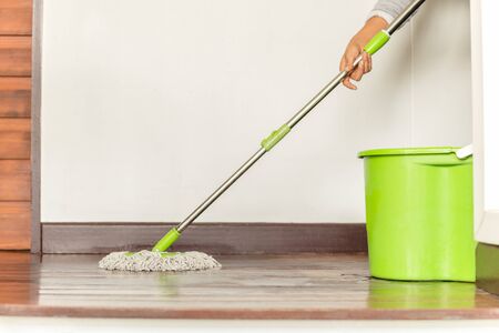 Woman's hand holding a mop cleaning house floorの写真素材