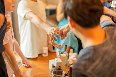 Man taking paper piece from plastic box with friends in backgroundの写真素材