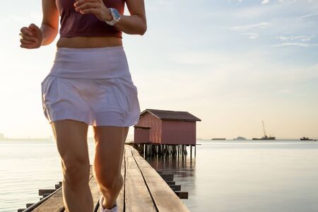Selected focus wooden hut with blurred sporty woman running on a bridge with ocean viewの写真素材