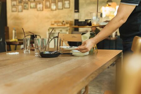 Waiter hand pick up dirty dishes on dinner restaurant.の写真素材