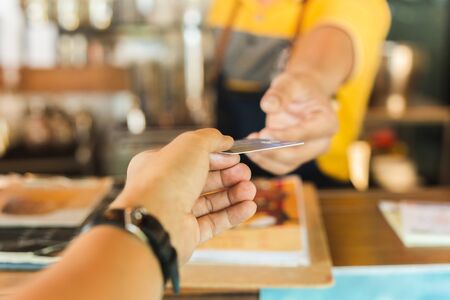 Male customer paying for their order with credit card in cafe.
