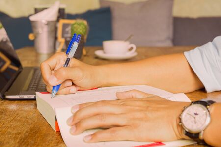 Businessman writing note on oreading book with laptop on table.の写真素材