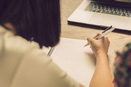 Woman write on notebook with laptop on table in cafe