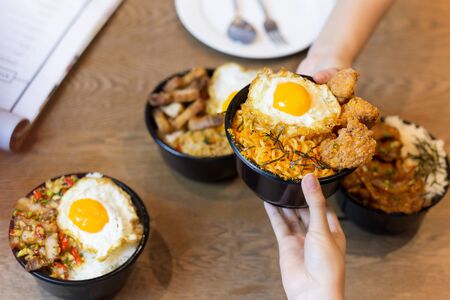 Shooting in low light couple holding tasty noodle with fried egg on top on wooden tableの写真素材