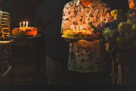 Short in low light family celebrating birthday to their mother with cake.の写真素材