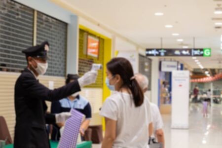 Security man check body temperature of people with infrared forehead thermometer Coronavirus...