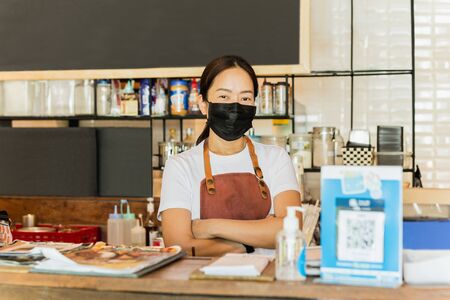 Women cafe owner wearing protective mask stand in counter Covid-19 conceptual.の写真素材