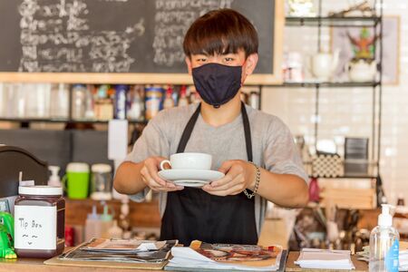 Social distance conceptual small business waiter serving coffee to customer in cafe.