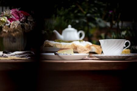 Afternoon tea basque burnt cheesecake and tea cup with teapot on wooden table.の写真素材