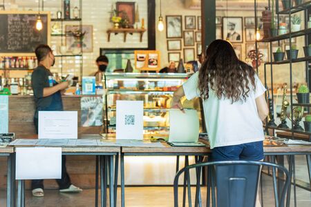 Social distance conceptual woman customer looking at menu with waiter standing in cafe.の写真素材