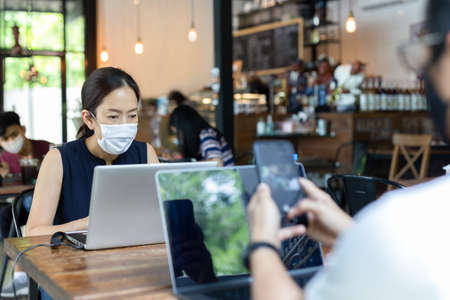 New normal woman wearing protective mask while working on laptop in cafe.の写真素材