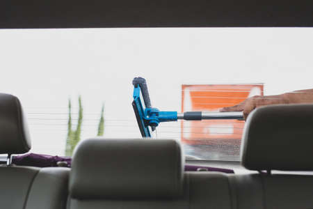 Employee using sponge to clean a car windscreen at gas station.の写真素材