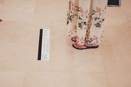 Woman standing on a floor with the words social distance, new normal concept
