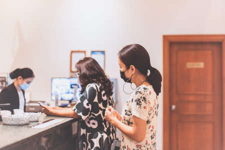 Woman in medical mask checking in at hotel new normalの写真素材
