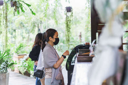 New normal women in protective face mask queuing at cafe counter.