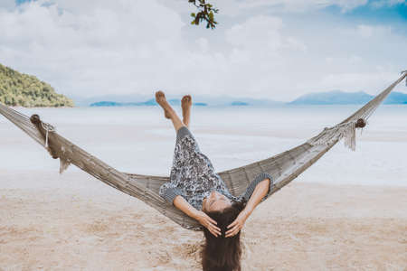 Woman relaxing in the hammock with her feet up in tropical beach on summer vacation.の写真素材