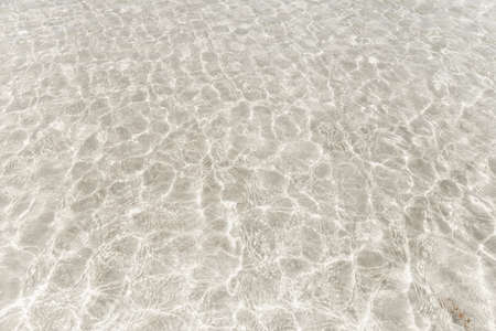 Top view surface of clear sea water reflections on shallow sandy beach.の写真素材