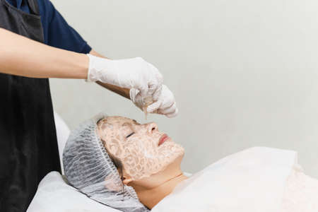Beauty portrait asian woman getting spa treatment with pipette oil on clean face.