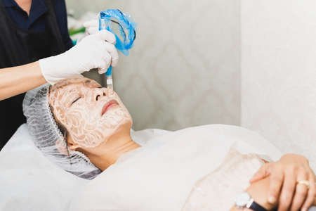 Woman having stimulating facial treatment at professional clinic.の写真素材