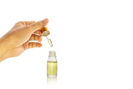 CBD Hemp oil hand holding droplet of Cannabis oil isolated in clipping path.