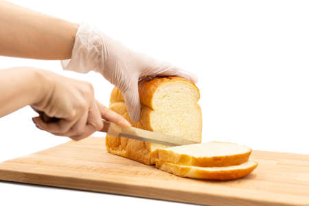 Hand cutting homemade Japanese Hokkaido bread on wooden board isolated.