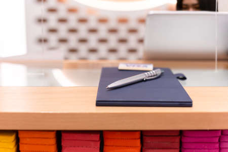 Selected focus pen on leather bill holder with cashier behid partition counter.の写真素材