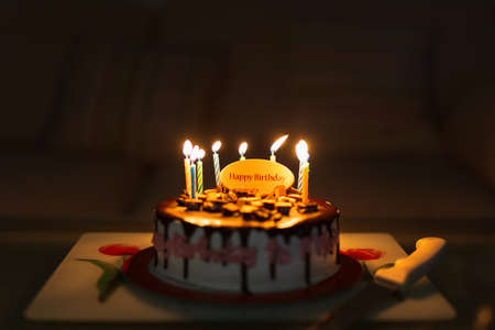 Birthday cake on black background with colorful candles lit.の写真素材