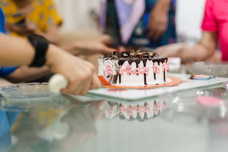 Woman is hand cutting birthday cake together with family.の写真素材