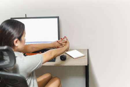 Woman stretching her hand while working on computer at home office.