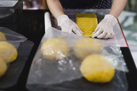 Womens hands roll out the pumpkin bread dough on kitchen table.