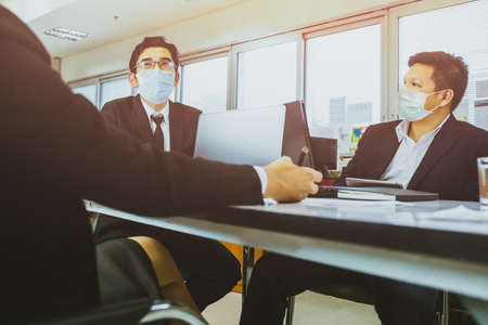 Team of businesspeople with protective masks during project meeting.の写真素材