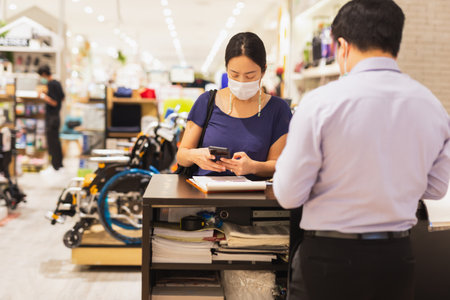 Customer in protective mask make payment with cell phone in shopping mall.の写真素材