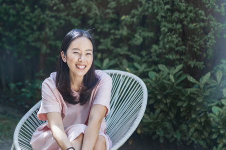 Portrait of woman sitting in the garden and smiling.の写真素材
