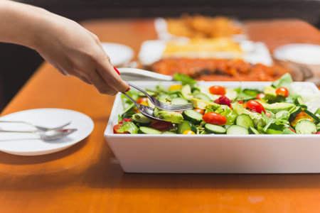 Woman hands taking mixed vegetable in a bowl with spoon and fork.の写真素材
