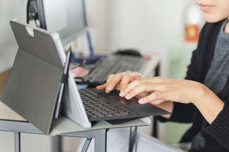 Businesswoman hands typing on laptop keyboard making at homeの写真素材