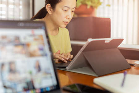 Asian business woman working on laptop computer at home.