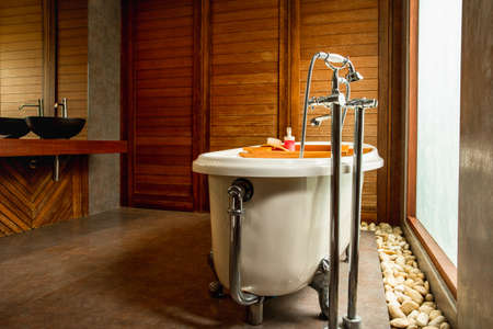 Vintage bathtub and large window with sinks in wooden bathroom.の写真素材