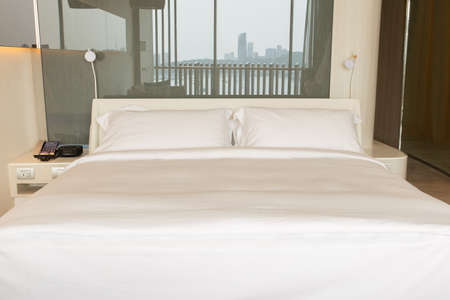 king size bed with white sheets and pillow on bed in hotel room.の写真素材