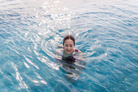 top view of portrait of a smiling woman in swimming pool with wet hair.の写真素材